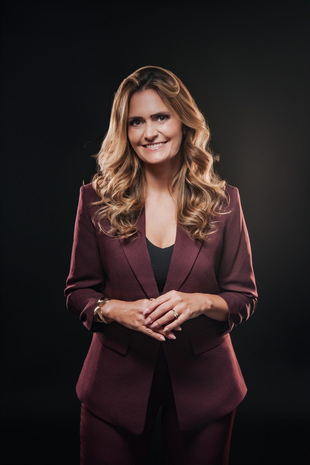 Portrait of Giselle Gartzke in a burgundy suit with her hands clasped